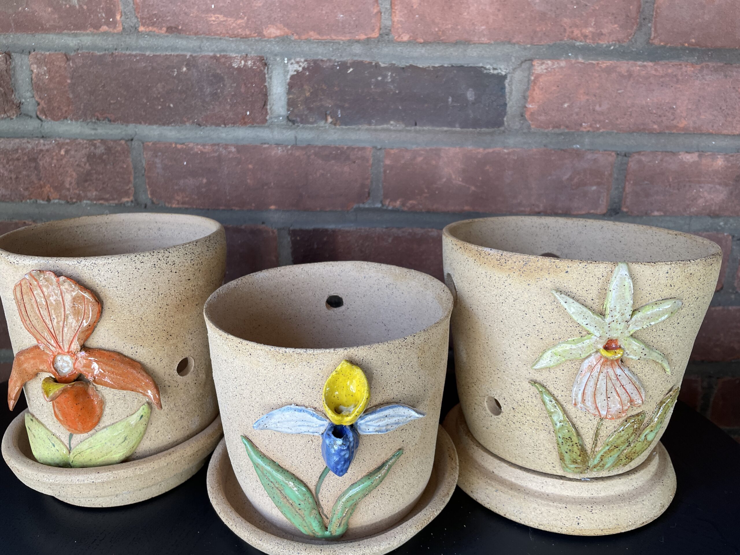 Three flower pots embellished with orchid flowers